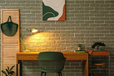 Odanın içindeki tuğla duvarın yanında rahat bir iş yeri.