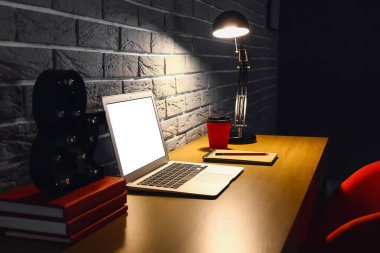 Odanın içindeki tuğla duvarın yanında dizüstü bilgisayarı olan rahat bir iş yeri.
