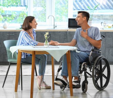 Fiziksel engelli genç bir adam ve karısı mutfakta.