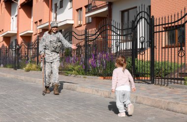 Küçük kız dışarıda askerî annesiyle buluşuyor.