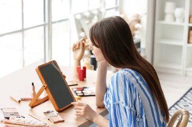 Soyunma odasında makyaj yapan güzel bir genç kadın.