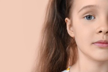 Bej arka planda küçük şirin bir kızın portresi, yakın plan.