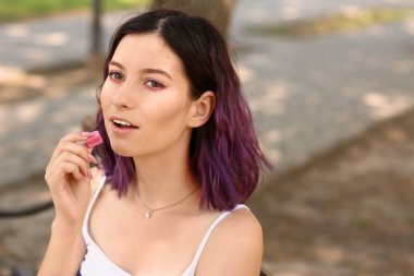 Parkta pembe sakızlı genç bir kadın, yakın plan.