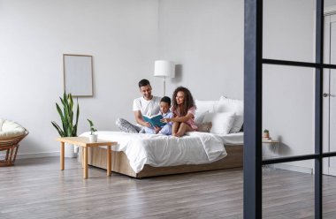 Mutlu ırklar arası aile kitapları yatakta okunur