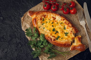 Lezzetli Ajarian khachapuri domatesli ve maydanozlu karanlık masa arkaplanı