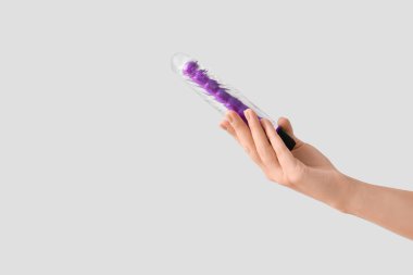 Işık arka planında vibratörü olan bir kadın el.