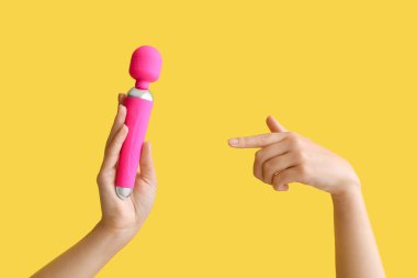 Renkli arka planda vibratörü olan kadın elleri