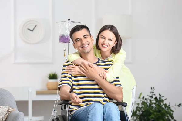 坐在轮椅上的年轻人和他的妻子在家里 — 图库照片