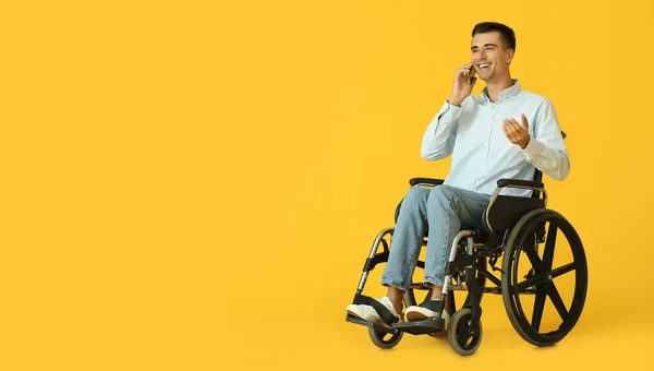 坐在轮椅上的年轻人通过电话在彩色背景下交谈 — 图库照片