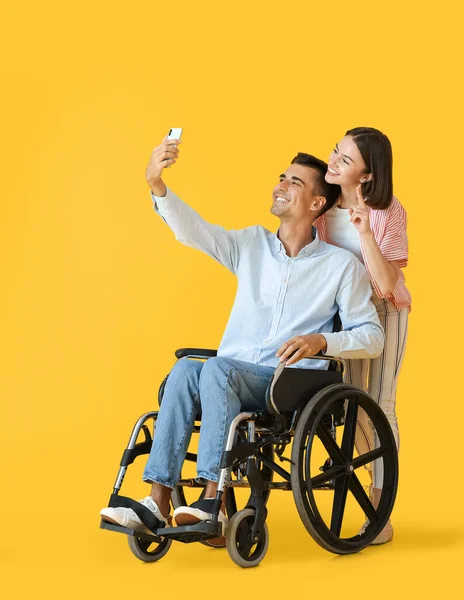車椅子の若い男と彼の妻は色の背景で自撮り — ストック写真