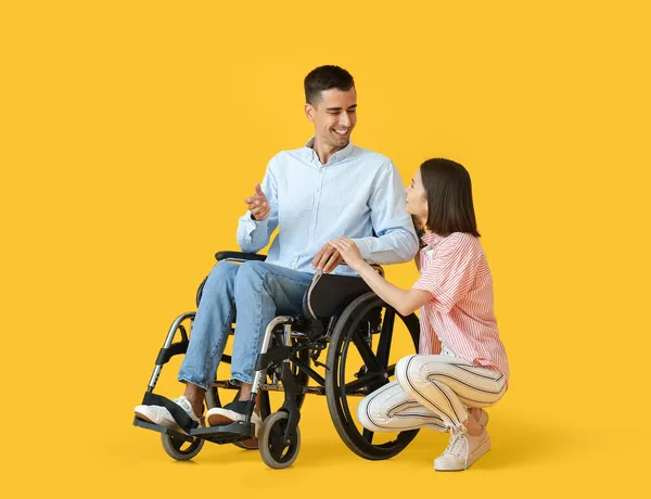 車椅子の若い男と色の背景の妻 — ストック写真