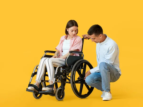 若い男と彼の妻は車椅子の色の背景に問題がある — ストック写真