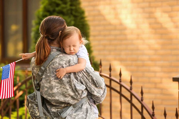 女兵和带着美国国旗的小女儿站在外面 — 图库照片