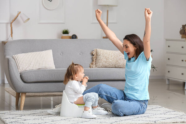 Mother potty training her little daughter at home