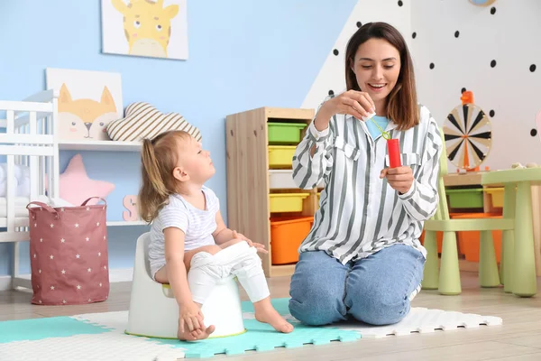 Mother potty training her little daughter at home