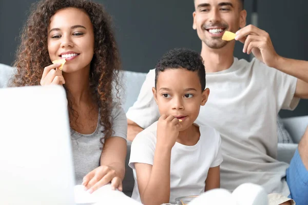 Feliz Família Interracial Com Laptop Comer Chips Casa — Fotografia de Stock