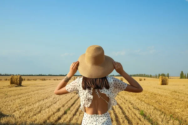 Hasat edilmiş tarla geçmişi olan şapkalı romantik genç bir kadın.