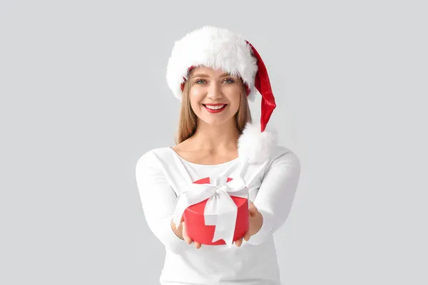 戴着圣诞礼帽 头戴灰色背景圣诞礼物的年轻漂亮女子 — 图库照片