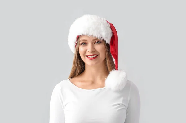 Noel Baba Şapkası Gri Arka Plan Üzerinde Güzel Genç Kadın — Stok fotoğraf
