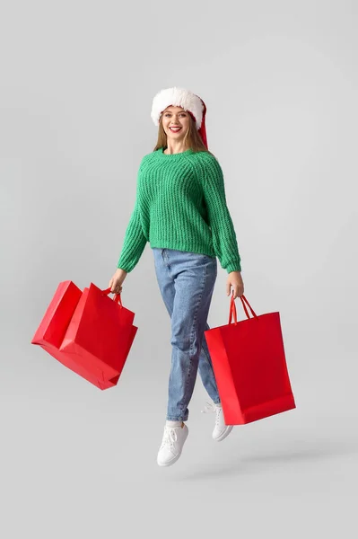 Jumping Young Woman Santa Hat Shopping Bags Grey Background — Stock Photo, Image