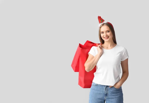 Mooie Jonge Vrouw Met Kerstdecor Boodschappentassen Grijze Achtergrond — Stockfoto