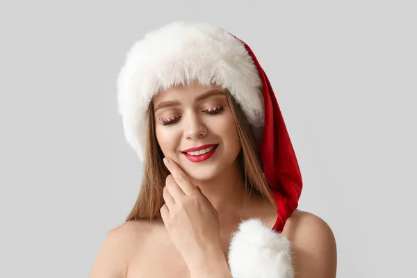 美丽的年轻女子 在灰色的背景上圣诞老人的帽子 — 图库照片