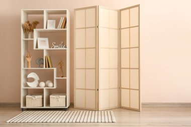 Odanın duvarına yakın katlanan ekran ve kitaplık şık