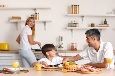 Küçük çocuk babasıyla mutfakta kahvaltı yapıyor.