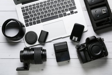 Beyaz ahşap arka planda fotoğraf teçhizatı olan dizüstü bilgisayar