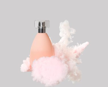 Gri arka planda hafif dumanlı parfüm şişesi