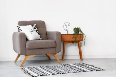 Şık bir iç mekan, komodin ve arka planda koltuk.