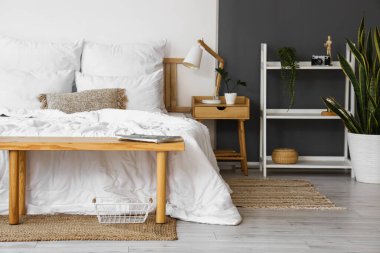 Hafif yatak odasının içinde şarjörü olan ahşap bir bank.