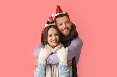 Şık kış kıyafetleri içinde mutlu genç bir çift ve renkli arka planda Noel süslemeleri.