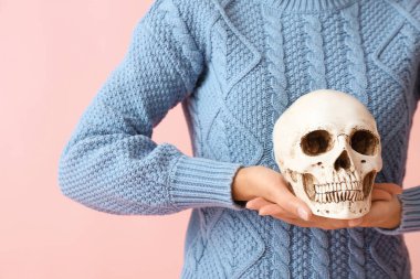 Renkli arka planda insan kafatasına sahip genç bir kadın, yakın plan.