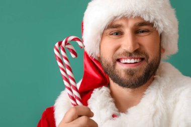 Yeşil arka planda şeker kamışlarıyla gülümseyen Noel Baba, yakın plan.