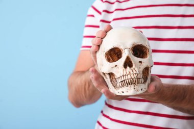 Mavi arka planda insan kafatasına sahip yakışıklı bir adam, yakın plan.