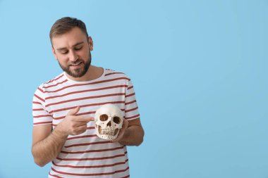 Mavi arka planda insan kafatasını gösteren yakışıklı bir adam.