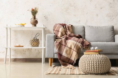 Rahat bir kanepe, masa, kitap ve gözlüklü bir şilte.