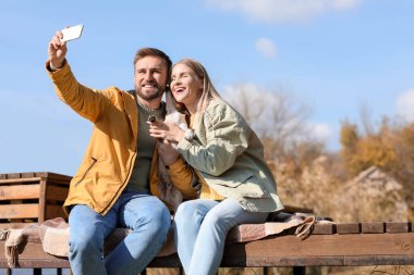 Güzel köpekli sevimli bir çift sonbahar günü selfie çekiyor.