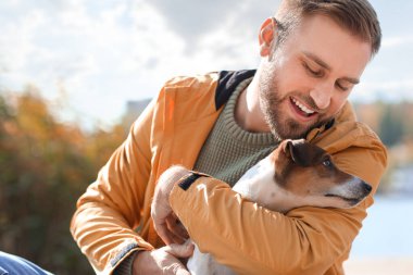 Sonbahar günü komik Jack Russel teriyeri olan yakışıklı bir adam.