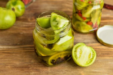 Konserve yeşil domatesli kavanozlar ahşap arka planda