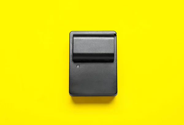 黄色の背景にカメラのバッテリーと充電器 — ストック写真
