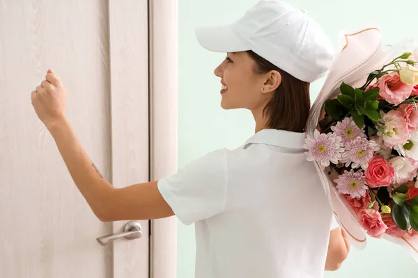 Kvinnlig Kurir Med Bukett Blommor Knackar Kundens Dörr — Stockfoto
