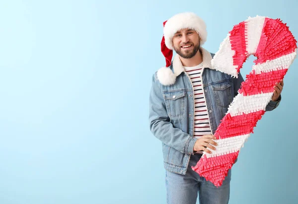 Schöner Mann Mit Weihnachtsmütze Mit Zuckerstange Pinata Auf Blauem Hintergrund — Stockfoto