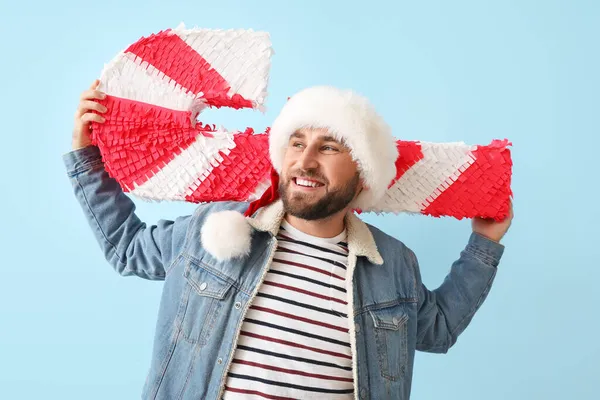 Schöner Mann Mit Weihnachtsmütze Mit Zuckerstange Pinata Auf Blauem Hintergrund — Stockfoto