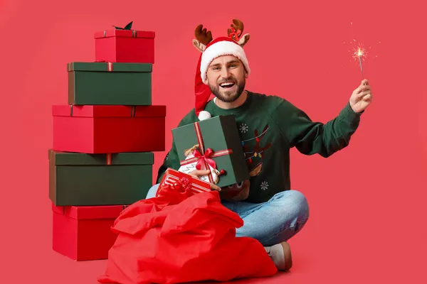 Schöner Mann Mit Weihnachtsgeschenken Wunderkerze Und Nikolaussack Auf Farbigem Hintergrund — Stockfoto
