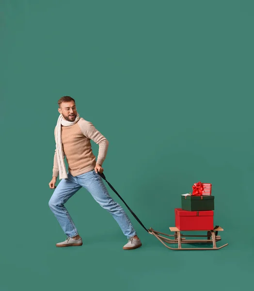 Mann Mit Weihnachtsgeschenken Auf Schlitten Vor Farbigem Hintergrund — Stockfoto