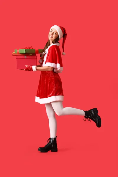穿着圣诞老人服装 头戴彩色背景圣诞礼物的年轻美女 — 图库照片
