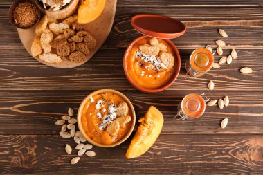 Lezzetli balkabağı kremalı kaseler ve ahşap zemin üzerinde tohumlar.