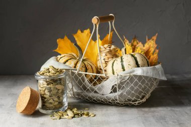 Gri arka planda taze sebzeli balkabağı tohumu ve sepeti.